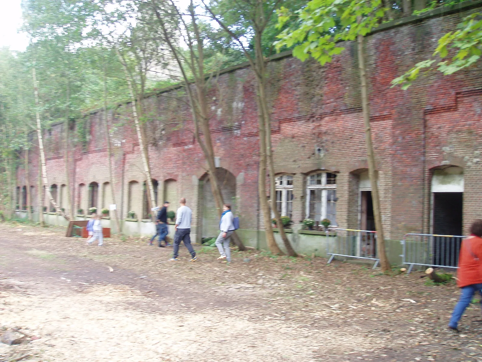 Brick facade with arched casemates of the ruined Fort van Walem, overrun by trees