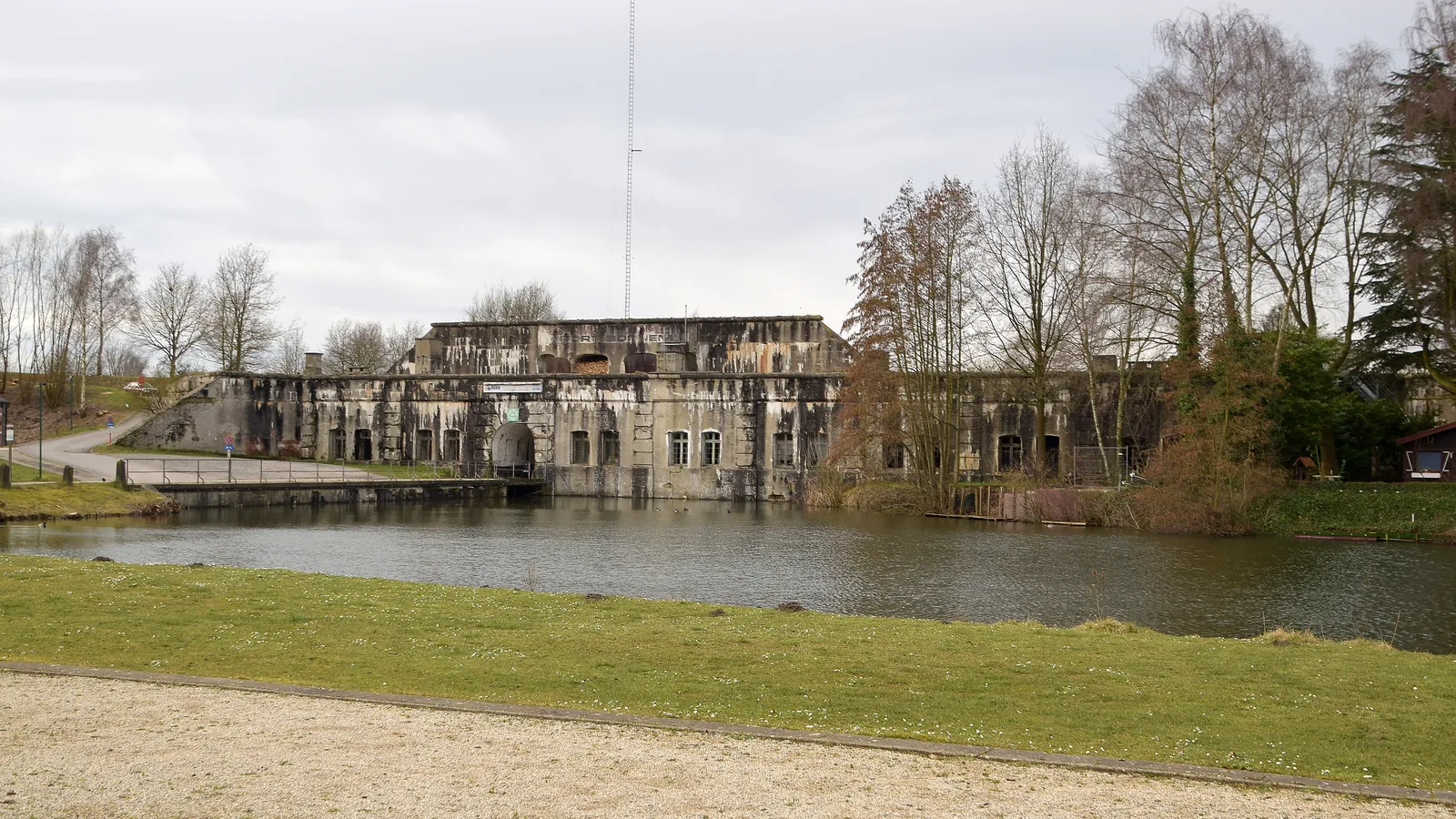 The Fort van Bornem, concrete building overrun by vegetation and reflected in its moats