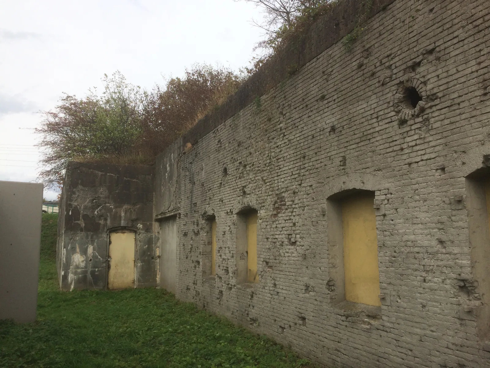 Overgrown brick wall riddled with bullet holes at the abandoned Fort Westervoort near Arnhem