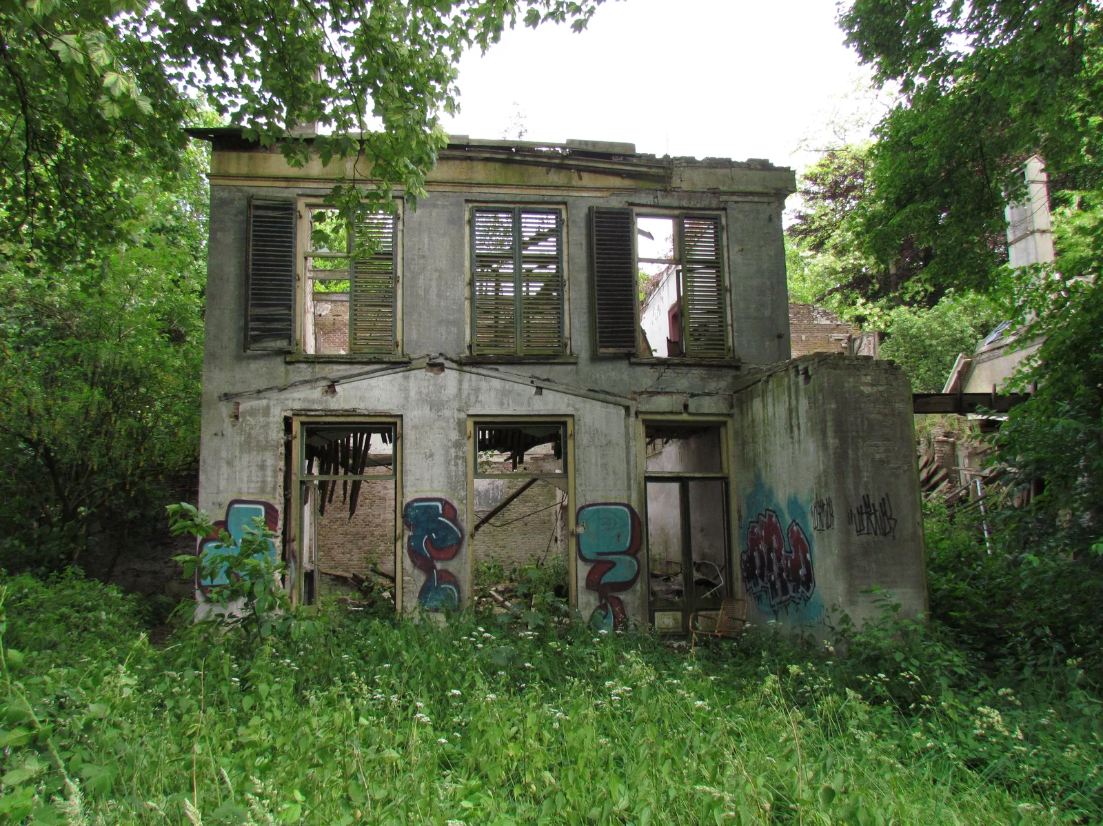 Graffiti-covered ruin of Hotel Dullemond in Laag-Soeren, roofless and overgrown in the woods