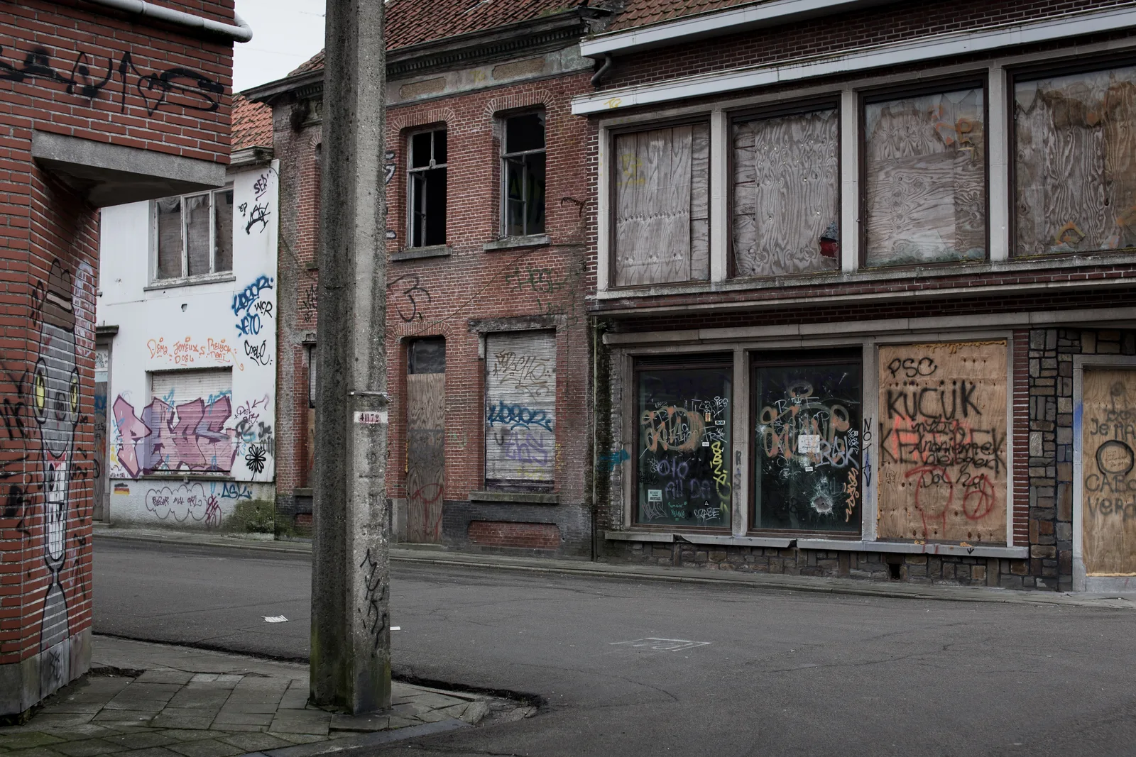 Street in the ghost town of Doel near Antwerp, brick houses with bricked-up windows covered in graffiti