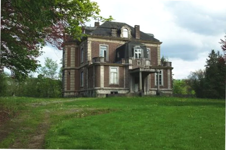 Facade of the abandoned Château del Marmol (villa of the black cat) in Ensival, Verviers: brick mansion with mansard roof and corner turret
