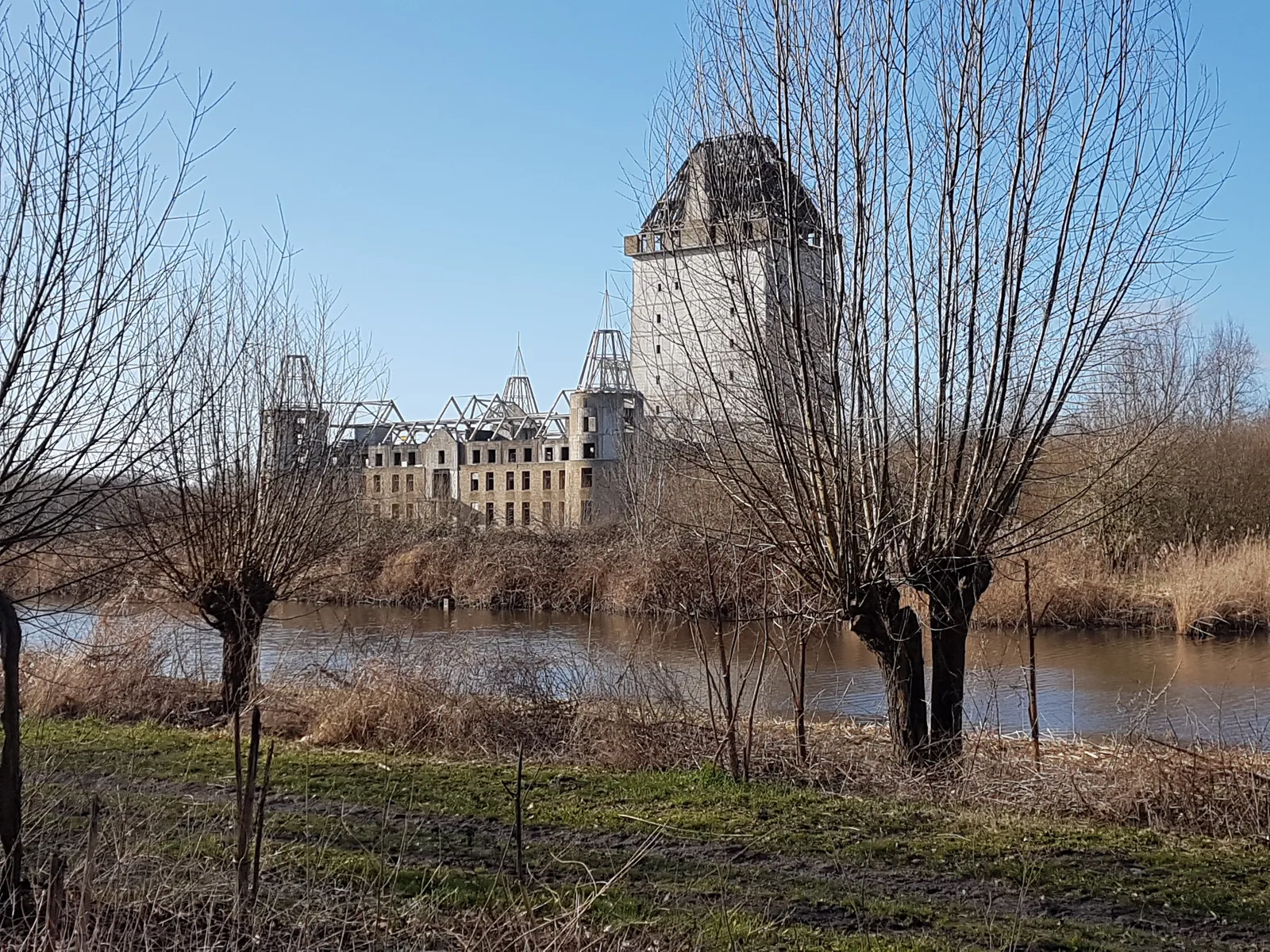 The unfinished concrete Kasteel Almere rising like a ruin above the water