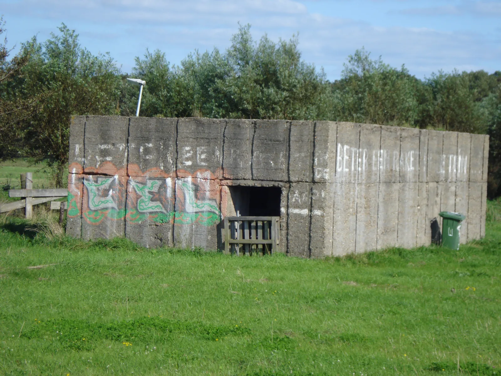 Graffiti-covered abandoned concrete bunker in an open field near the Staelduinse Bos in 's-Gravenzande