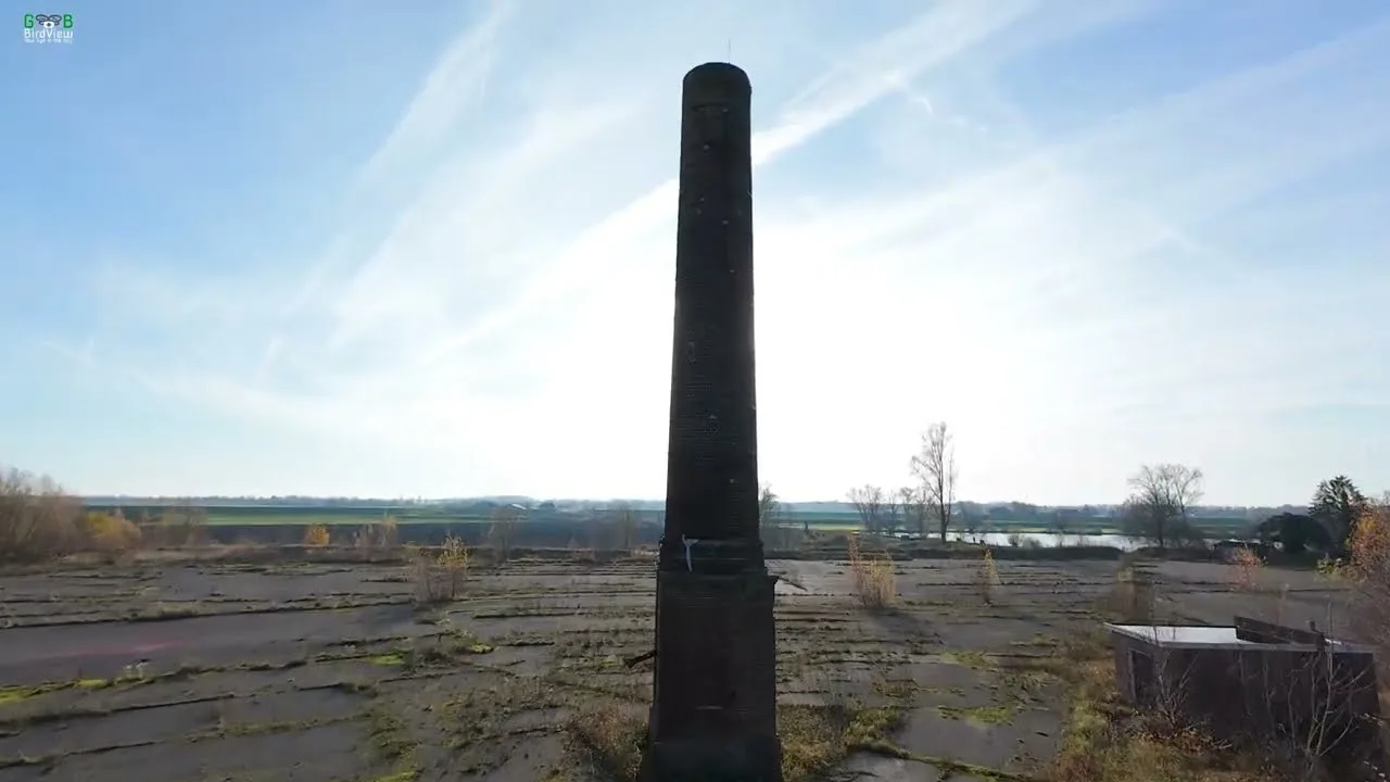 The tall brick chimney of the abandoned De Roodvoet brickworks above the derelict site on the Lek